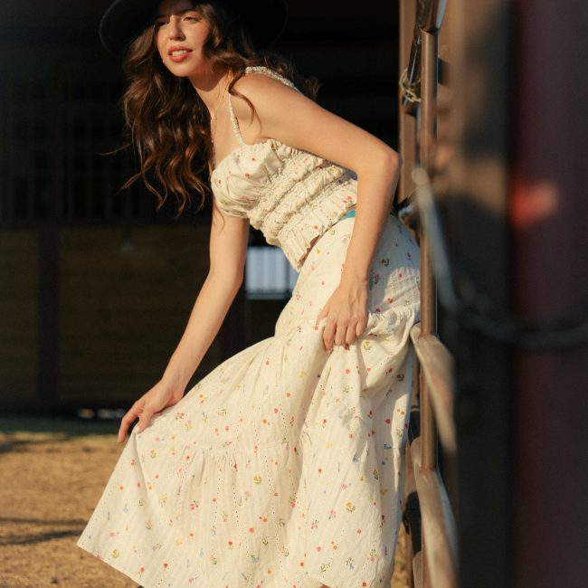 Western model in a white floral dress, black boots, and a black cowboy hat